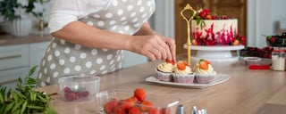 kvinne dekorere cupcakes med jordbær
